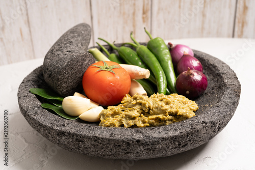 Indonesian green chilli paste on the stone mortar and pestle . 