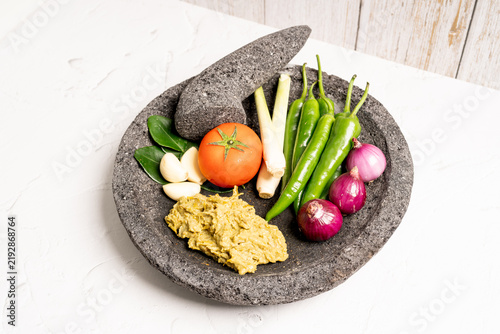 Indonesian green chilli paste on the stone mortar and pestle . 