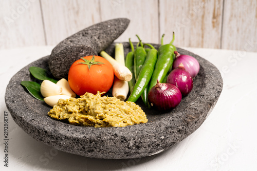 Indonesian green chilli paste on the stone mortar and pestle . 