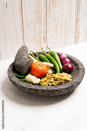 Indonesian green chilli paste on the stone mortar and pestle . 