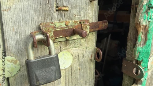 Rusty latch and padlock on an old wooden barn door