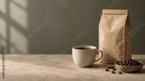 Blank brown paper coffee bag and mug filled with hot dark beverage sitting beside a small bowl of freshly roasted beans on a textured stone table illuminated by warm morning sunlight