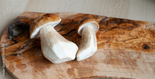 Konstfotografi Fresh porcini mushrooms after washing lie on a wooden cutting board on a table