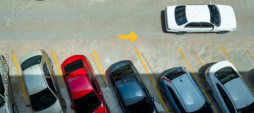 фотографія Top view of cars parked in outdoor concrete parking lot with yellow space lines and directional arrow