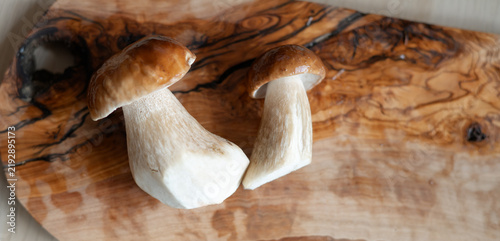 Konstfotografi Fresh porcini mushrooms after washing lie on a wooden cutting board on a table