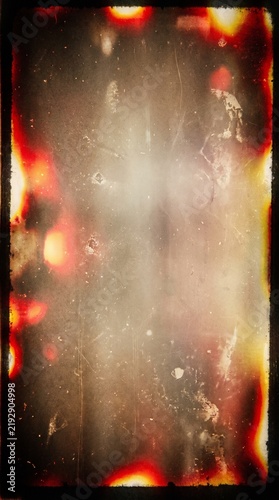 Vintage analog film background texture with heavy light burns, dust, and dark frame border