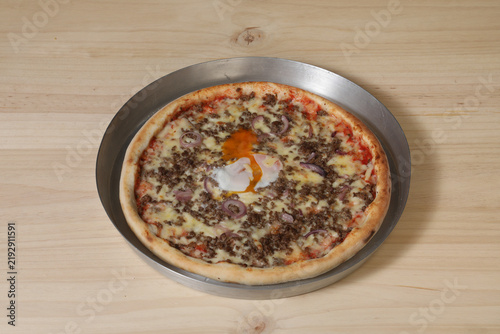 Картината върху платно Un plat de fast-food avec une pizza à la viande sur une table en bois