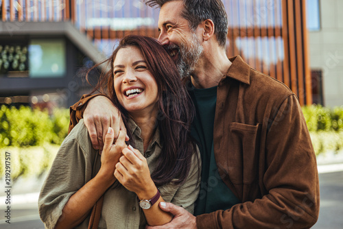 Fotografie Laughing Couple Embracing on Urban Street Showing Love, Happiness and Affectiona