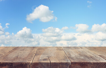 Empty rustic table in front of blue sky with clouds. product display.