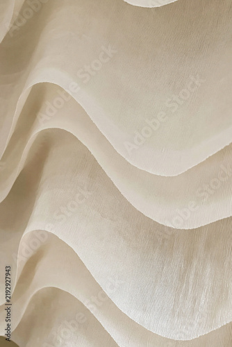 Close-up view of layered ivory fabric reveals soft flowing curves, delicate texture, translucency, and elegant minimalist composition.