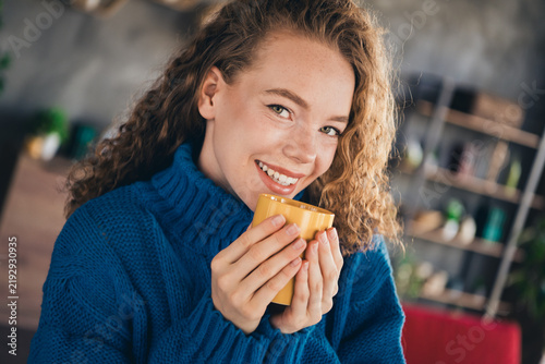 Foto Joyful woman in a cozy blue sweater enjoys a morning coffee at home, bathed in d