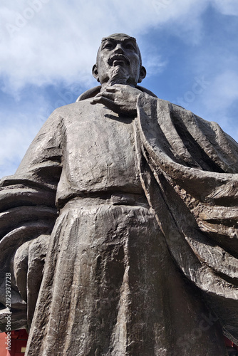 Quadro su tela Bronze statue of ancient Chinese scholar in traditional robe under blue sky