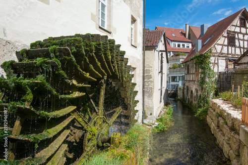 Historic water wheel beside a clear stream in Bad Urach