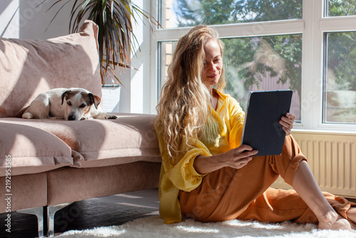 Foto Woman with tablet relaxing at home with her dog on sofa