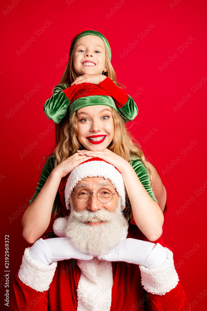 Obraz premium Santa Claus with smiling daughters and elves stacked together in festive red and green holiday portrait