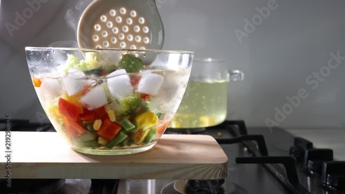 Blanching vegetables in hot water in a glass bowl