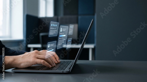 A person's hands type on a laptop keyboard, with digital profile cards floating holographically above the screen, symbolizing online data management or digital identity.