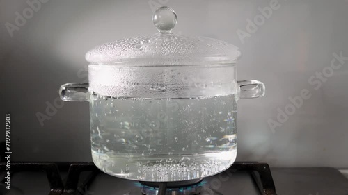 Boiling water in a transparent glass pot on a gas stove