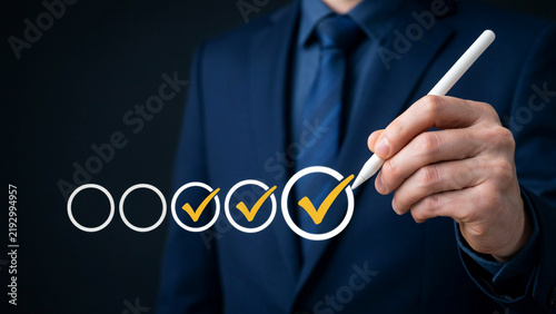 Businessman's hand checking off tasks in a row with a stylus pen against a dark background