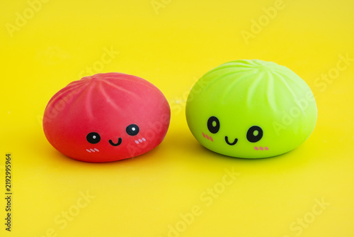Two soft anti-stress toys in the shape of a dumpling with a happy face on a yellow background