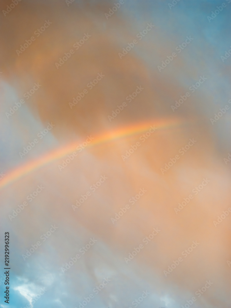 Obraz premium Faint Rainbow Beneath Dramatic Storm Clouds After Rain at Sunrise