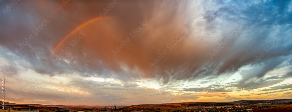 Obraz premium Panoramic Rainbow and Dramatic Storm Clouds at Sunrise After Rain