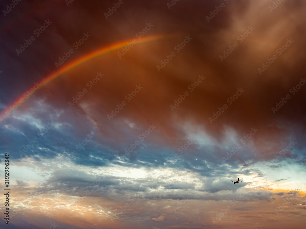 Obraz premium Faint Rainbow Beneath Dramatic Storm Clouds After Rain at Sunrise