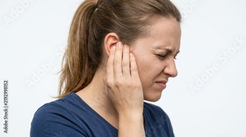 Young woman suffering from earache and hearing loss, touching her ear in pain against white background
