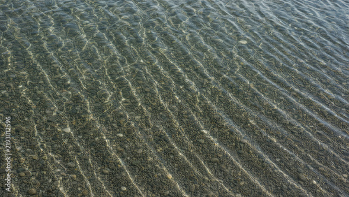 Sunlit Ripples over Pebbles beneath Clear Shallow Water
