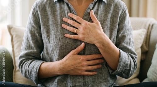 Woman with hands on chest experiencing acute pain or discomfort. Image symbolizes potential heart attack, anxiety, or stress, needing medical attention