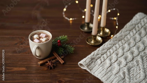 Obraz na płótnie A steaming mug of hot cocoa with marshmallows sits on a dark wooden table next t