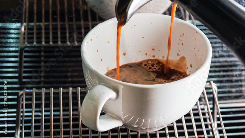Close-up of espresso pouring from the coffee machine into a coffee cup. Professional coffee brewing