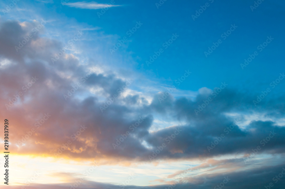 Obraz premium Sunset sky landscape background. Dark grey clouds and glowing bright golden sunlight of the dramatic evening atmosphere