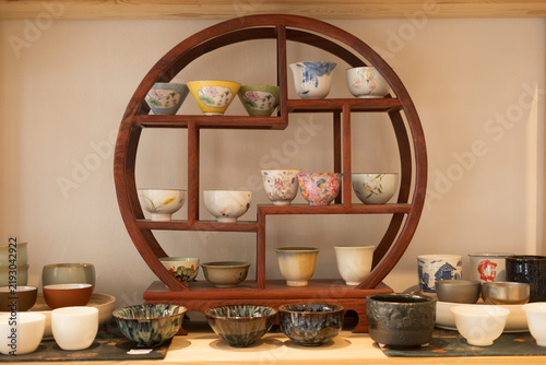Foto Ceramics on a round wooden shelf, displaying handmade bowls and cups in varied c