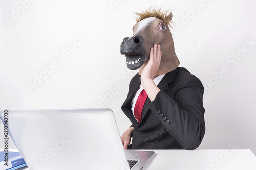 Принти на полотні Businessman Wearing Horse Head Mask Working at Laptop in Office