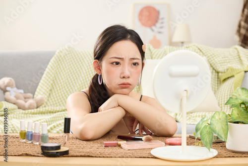 Foto Bored Young Woman Resting at Makeup Table with Cosmetics