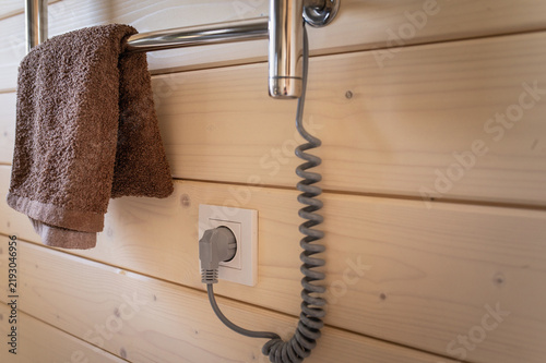 An electric towel warmer mounted on a wood-clad bathroom wall. Home coziness and comfort.