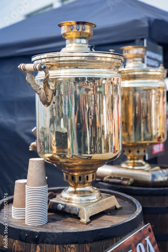 Obraz na plátně Brass samovar on wooden barrel with paper cups at outdoor market