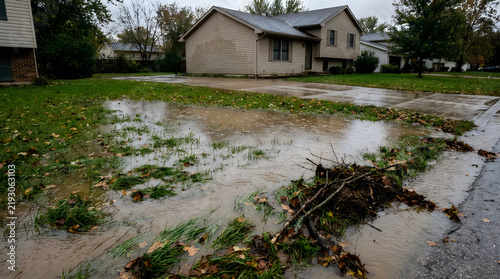 Flooded suburban front yard and street with water accumulation after heavy rainfall