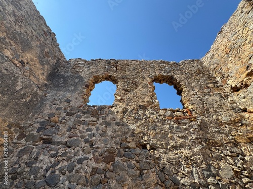 Canvastavla Scenic view of the historic Red Tower (Kızılkule) from inside the ancient fortress walls in Alanya, Turkey, featuring a blue sky, stone walkway, and coastal harbor background
