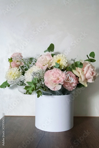 Foto Beautiful floral arrangement in a white hat box with pink and white flowers, roses, and eucalyptus on a neutral background
