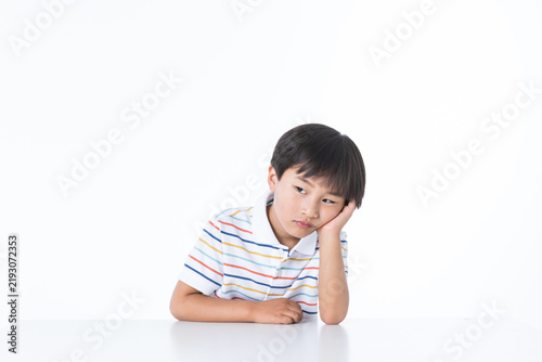 Bored Young Boy Resting Head on Hand at White Desk