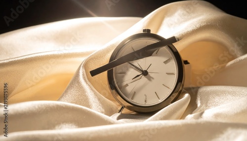 Round clock resting on soft silk fabric folds.