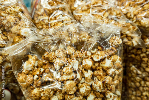 Quadro su tela Popcorn coated with caramel, packed in transparent plastic bags, showcasing a sweet and crunchy snack ready for consumption or sale