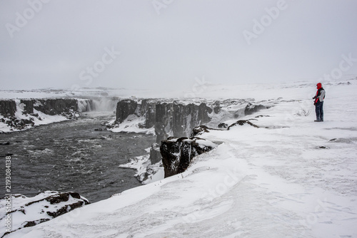 Hiker watching Selfoss waterfall in the snowy canyon in Iceland