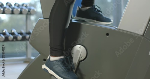 Right foot starting on elevated pedal and pressing down, stepper rotating for steady gym workout