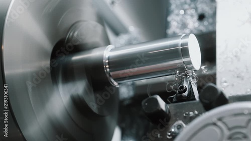 Close-up of metal turning process on an industrial lathe machine with a rotating metal workpiece and cutting tool. Precision machining, metalworking and manufacturing process in modern industry.