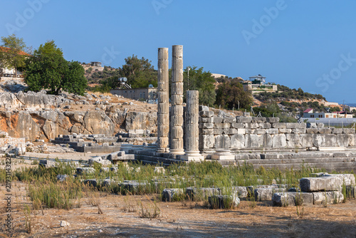 Foto Weathered broken stone columns rise from Patara ruins against a bright blue sky