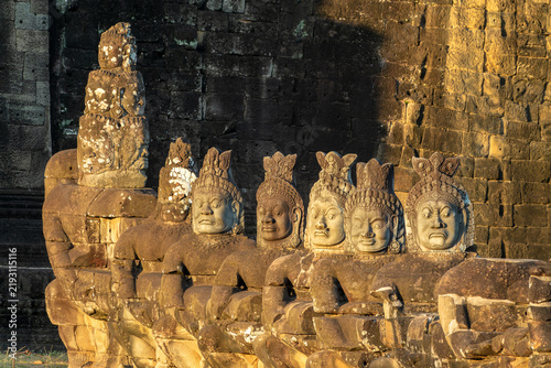 Canvastavla Asuras head statues in a row at Angkor Thom South gate, demon faces at sunset in