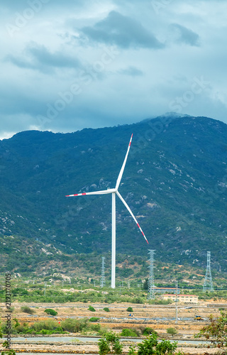 Vietnam's modern energy industry - traditional electric lines from a hydroelectric power plant and wind turbines on mountain slopes